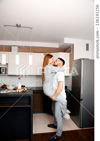 Couple sharing a joyful moment in a modern kitchen while preparing breakfast together in the morning light 136191256
