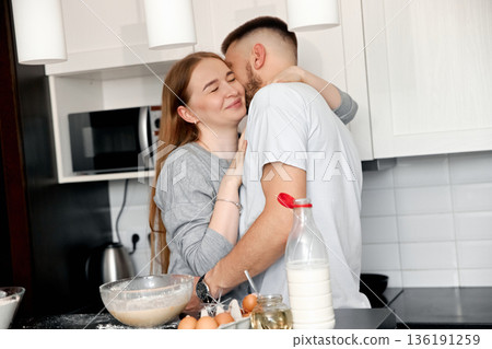 Couple sharing a warm embrace while cooking together in a cozy kitchen in the afternoon light Couple sharing a warm embrace while cooking together in a cozy kitchen in the afternoon light 136191259