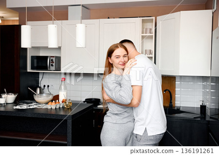 Couple enjoying a cozy moment in a modern kitchen while preparing breakfast together with eggs and various utensils on the counter Couple enjoying a cozy moment in a modern kitchen while preparing breakfast together with eggs and various utensils on the counter 136191261