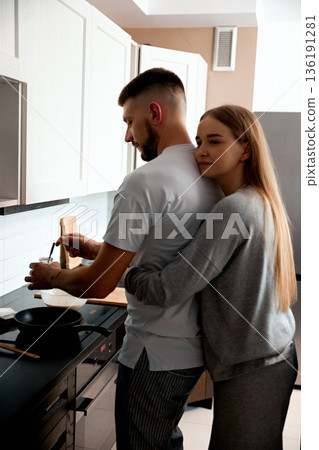 Couple cooking together in modern kitchen while enjoying time and sharing a moment of connection during evening hours 136191281