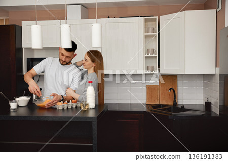 Couple Preparing a Meal Together in a Modern Kitchen During a Sunny Afternoon Couple Preparing a Meal Together in a Modern Kitchen During a Sunny Afternoon 136191383