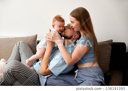 Loving family moment with parents and baby sharing joy and affection on a cozy couch in a bright living room healthy family concept Loving family moment with parents and baby sharing joy and affection on a cozy couch in a bright living room healthy family concept 136191393