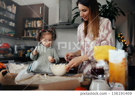 Mother and child bake together in a kitchen, mixing ingredients and enjoying a fun activity at home during the afternoon Mother and child bake together in a kitchen, mixing ingredients and enjoying a fun activity at home during the afternoon 136191409
