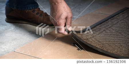 A person getting a key from under their mat A person getting a key from under their mat 136192306