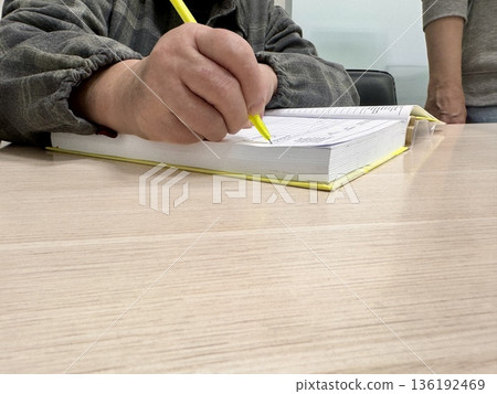 an elderly woman puts her signature in a notary's notarial book an elderly woman puts her signature in a notary's notarial book 136192469