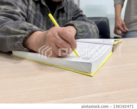 an elderly woman puts her signature in a notary's notarial book an elderly woman puts her signature in a notary's notarial book 136192471