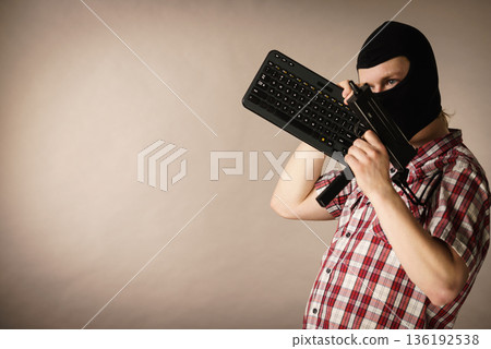 Man in balaclava holding keyboard and gun 136192538