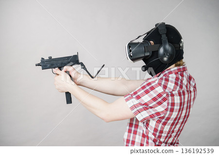 Gamer man wearing VR holding gun Gamer man wearing VR holding gun 136192539