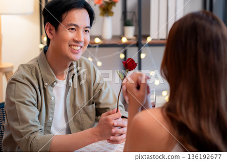 Romantic asian man giving rose to woman during dinner, surprise gift for Valentine's Day. Romantic asian man giving rose to woman during dinner, surprise gift for Valentine's Day. 136192677