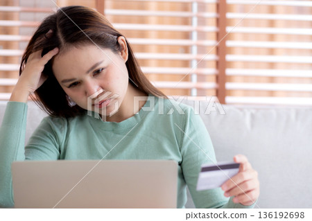 Young asian woman holding credit card or debit card with stress about loan and expense. Young asian woman holding credit card or debit card with stress about loan and expense. 136192698
