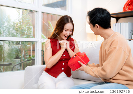 Happy asian man giving heart gift box to girlfriend celebrating Valentine's Day or anniversary. 136192736