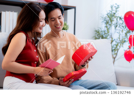 Asian young man and girlfriend celebrating Valentine's Day, woman holding card and gift box. Asian young man and girlfriend celebrating Valentine's Day, woman holding card and gift box. 136192746
