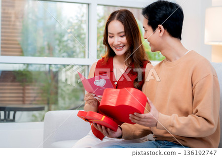 Asian young man and girlfriend celebrating Valentine's Day, woman holding card and gift box. Asian young man and girlfriend celebrating Valentine's Day, woman holding card and gift box. 136192747