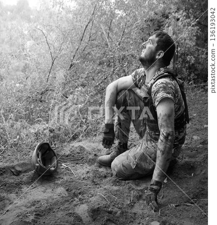 Young soldier sitting on the ground Young soldier sitting on the ground 136193042