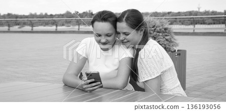 Two girls using a phone 136193056