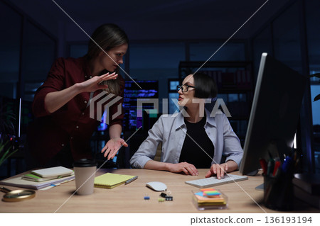 Two colleagues engage in a deep discussion during late-night work hours in a modern office setting Two colleagues engage in a deep discussion during late-night work hours in a modern office setting 136193194
