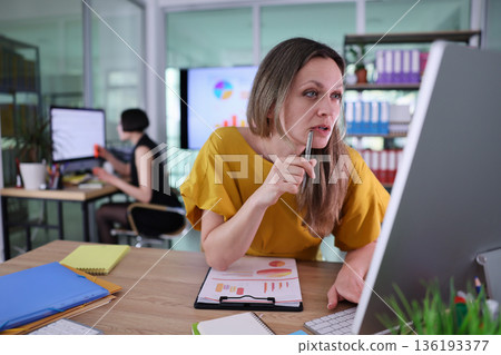 Focused woman analyzing data and collaborating in a modern office environment during a productive daytime meeting Focused woman analyzing data and collaborating in a modern office environment during a productive daytime meeting 136193377