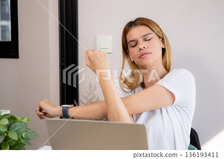 Portrait young caucasian businesswoman taking a break after overworked with stretching arm. 136193411