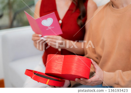 Asian young man and girlfriend celebrating Valentine's Day, woman holding card and gift box. 136193423