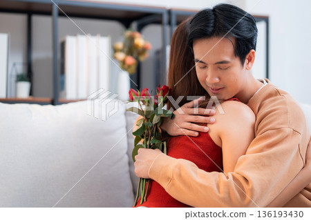 Happy asian couple hug holding rose flower for valentine's day or anniversary at home. 136193430