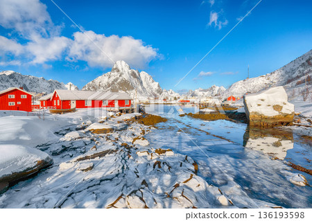 Outstanding winter sunny view on Reine Village and Gravdalbukta bay with cracked ice. Outstanding winter sunny view on Reine Village and Gravdalbukta bay with cracked ice. 136193598