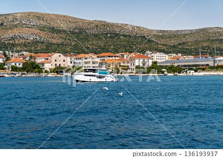 Modern yacht cruising along Dalmatian coast near Split with mountains and waterfront houses Modern yacht cruising along Dalmatian coast near Split with mountains and waterfront houses 136193937