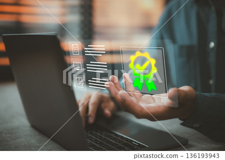 Quality assurance concept with digital certificate and checkmark hologram over laptop 136193943