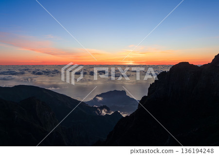 Sunrise above cloud ocean from Miradouro do Pico do Arieiro Madeira with warm horizon colors 136194248