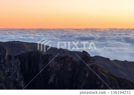 Sea of clouds covering mountain ridge at sunrise from Pico do Arieiro lookout in Madeira Portugal Sea of clouds covering mountain ridge at sunrise from Pico do Arieiro lookout in Madeira Portugal 136194251