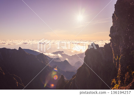 Rocky ledge viewpoint at Pico do Arieiro shows hikers over cloud ocean at sunrise Madeira view Rocky ledge viewpoint at Pico do Arieiro shows hikers over cloud ocean at sunrise Madeira view 136194257