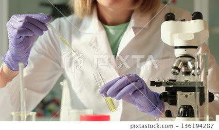 Scientist conducting a fascinating experiment in a bright laboratory filled with colorful samples and advanced equipment 136194287