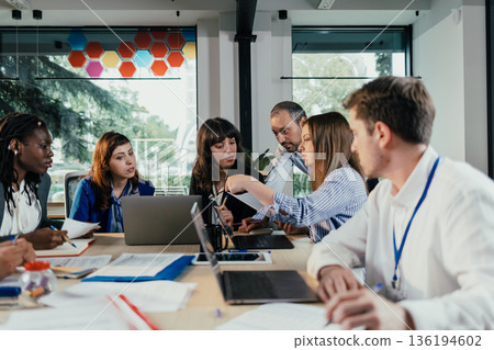 Business people collaborating during busy corporate meeting Business people collaborating during busy corporate meeting 136194602