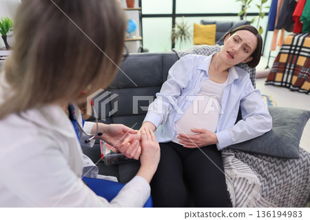 Expecting mother receives care and support during a prenatal check-up in a cozy clinic setting 136194983