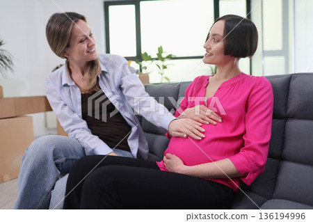 Joyful moments shared between friends during a serene pregnancy celebration in a cozy living room setting 136194996