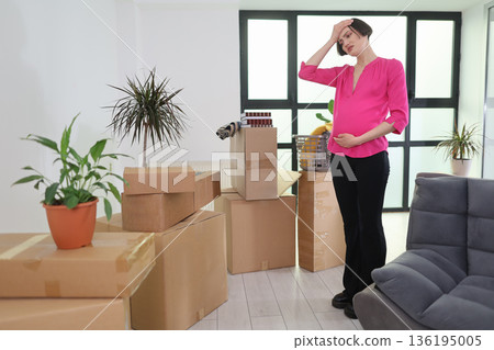 Expecting mother feels overwhelmed surrounded by moving boxes in a bright, uncluttered living space Expecting mother feels overwhelmed surrounded by moving boxes in a bright, uncluttered living space 136195005