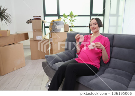 Expecting mother enjoys a cozy moment knitting at home surrounded by moving boxes Expecting mother enjoys a cozy moment knitting at home surrounded by moving boxes 136195006