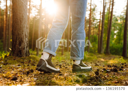 Hiker's boots stepping on a blanket of fallen autumnal orange leaves in the forest. Travel 136195570