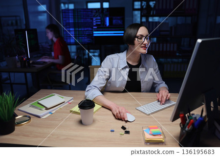 Creative coding session in a modern workspace during nighttime with focused individuals working on computers Creative coding session in a modern workspace during nighttime with focused individuals working on computers 136195683
