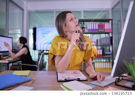 Creative brainstorming session in a modern office, where ideas come to life amidst charts and focused discussions 136195723