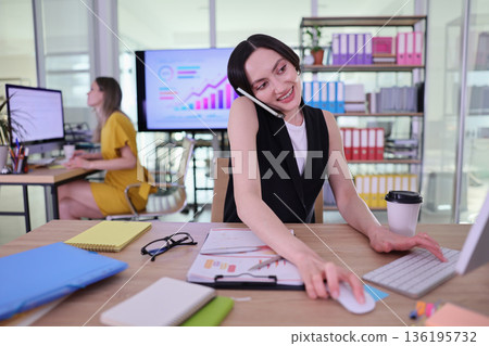 Busy professionals engage in teamwork and multitasking in a modern office setting while managing tasks and communications efficiently Busy professionals engage in teamwork and multitasking in a modern office setting while managing tasks and communications efficiently 136195732