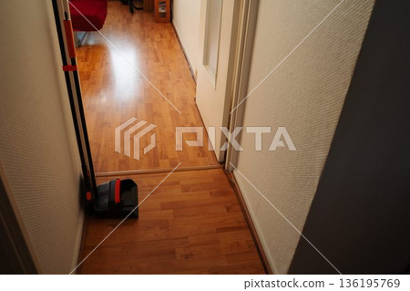 Tall broom and dust pan standing in an apartment corridor. Simple everyday home interior scene showing basic cleaning tools stored indoors for routine household maintenance. Tall broom and dust pan standing in an apartment corridor. Simple everyday home interior scene showing basic cleaning tools stored indoors for routine household maintenance. 136195769