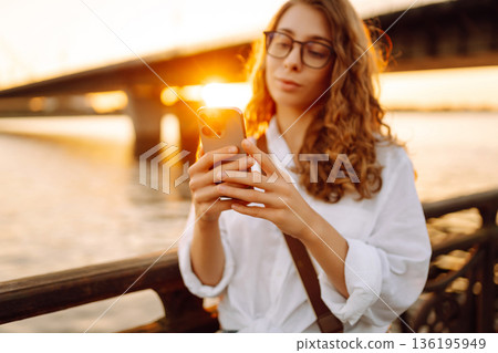 Phone in woman's hands. Communication with friends. Travel, tourism, technology, blogging concept. Phone in woman's hands. Communication with friends. Travel, tourism, technology, blogging concept. 136195949