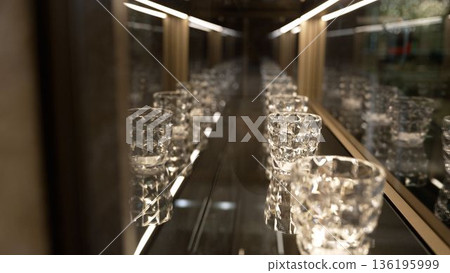Ornate crystal drinking glasses displayed in a modern lit showcase Ornate crystal drinking glasses displayed in a modern lit showcase 136195999