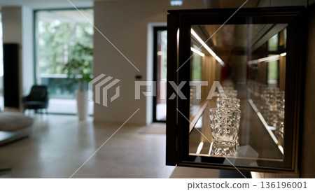Luxurious crystal glasses displayed in illuminated kitchen cabinet 136196001