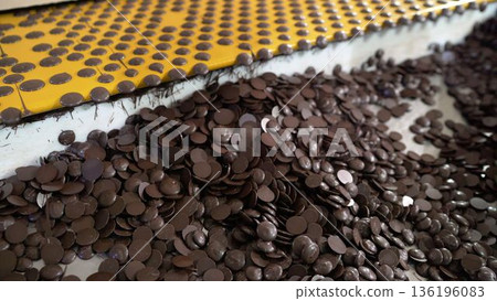 Chocolate chips accumulating from industrial conveyor belt 136196083
