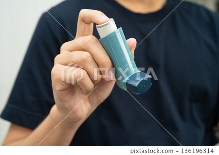 Asthma and chronic obstructive pulmonary disease COPD, Asian young man using metered dose inhaler MDI. Asthma and chronic obstructive pulmonary disease COPD, Asian young man using metered dose inhaler MDI. 136196314