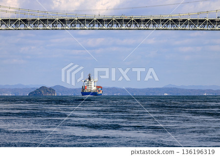 A large ocean liner departed, passing under Kanmon bridge toward the sea at Kitakyushu, Japan. 136196319