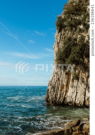 Seaside Cliff Landscape With Craggy Rock Face And Blue Ocean Under Bright Sky 136196641