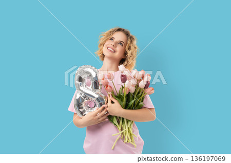 Woman holds flowers and a balloon while celebrating March 8 136197069
