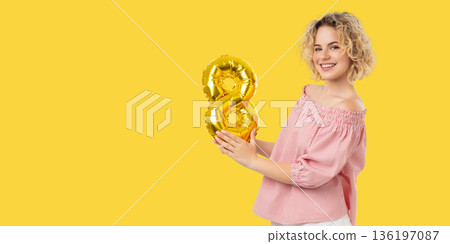 Woman smiles and holds a golden number balloon in celebration Woman smiles and holds a golden number balloon in celebration 136197087